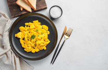 Scrambled eggs on a plate with parsley for a healthy breakfast or brunch. Top view, copy space.