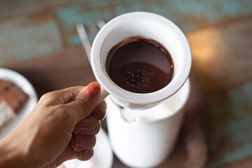 melted chocolate in white ceramic jar held by hand.