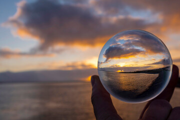 View on a beautiful sunset over ocean coast through a glass ball. Creative photography. Dusk time....