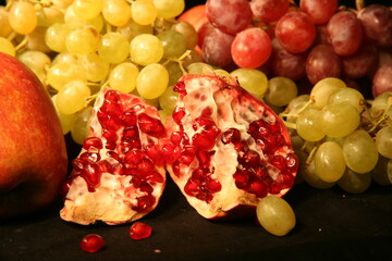 ripe grapes and pomegranates on a black background