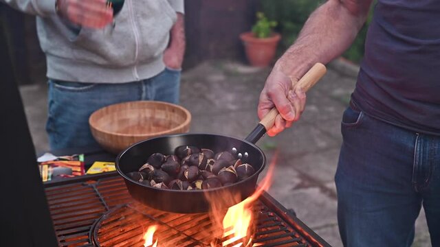 Roasted chestnuts and maroni over the fire in a special steel pan. Traditional Italian autumn delicacies. Party at a country house with friends, barbecue and wine. High quality 4k footage