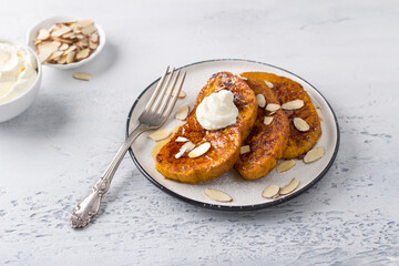 Sweet pumpkin toast with honey and cream, sprinkled with powdered sugar and almond petals on a light blue textured background. Delicious homemade breakfast
