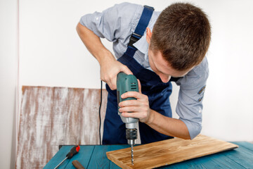 Handyman in blue uniform works with electricity automatic screwdriver. House renovation conception.