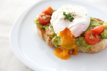 Poached eggs with avocado on toast in white background