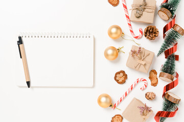 Obraz na płótnie Canvas Minimal creative flat lay of winter christmas traditional composition and new year holiday season. Top view open mockup black notebook for text on white background. Mock up and copy space photography.