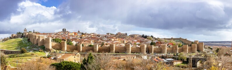 Fototapeta na wymiar Panoramic view of the Spanish city Avila surrounded by its medieval walls with a dark and cloudy sky on a bad weather day