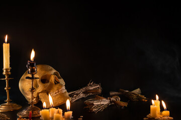 Old Skull and candle with incense on old altar plate which has dim light. Select focus, black...