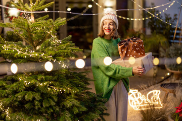 Woman with gift boxes at New Year's decorated backyard