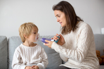 Mother, helping little toddler child with inhaler with spacer