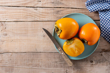 Fresh persimmon fruit on wooden table. Copy space