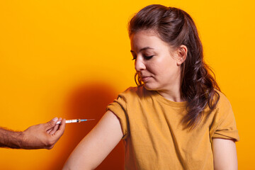 Hands of doctor with syringe and needle vaccinating woman on camera. Caucasian person looking at vaccine shot injection for protection and immunity against coronavirus. Adult at vaccination