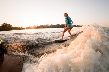 fit woman masterfully riding wakesurf on splashing river water. Active water sports