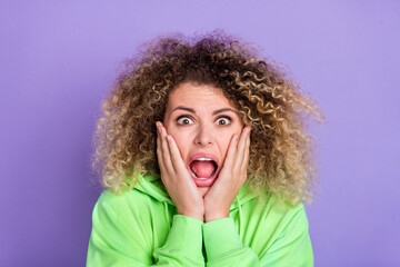 Photo of frightened girl wear green sweatshirt arms cheeks open mouth shouting isolated violet color background