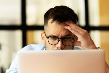 Young businessman using laptop in his office. Tired man working in the office