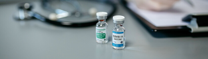 Two different vials of coronavirus vaccine on a female doctor's table