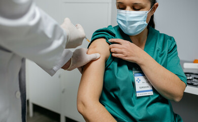 Female surgeon receiving coronavirus vaccine at doctor's office