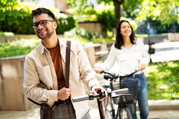 Fototapeta premium Happy young couple outdoors. Loving couple with bicycle in the park