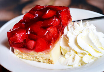 Auf einem Teller liegt ein leckeres Stück Erdbeerkuchen mit Schlagsahne.
