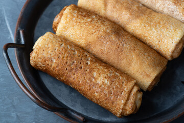 Thin pancakes or crepes stuffed with cottage cheese on grey background