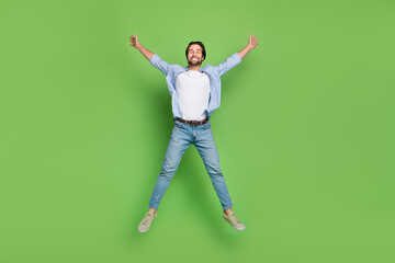 Full size photo of young man have fun jump up wear casual clothes isolated over green color background