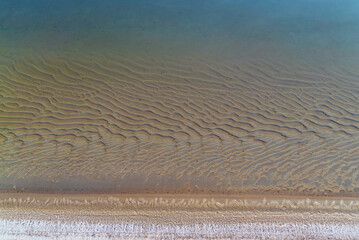 Thin ice on the water of a sand pit with a transparent sandy bottom . Leningrad region, Vsevolozhsk.