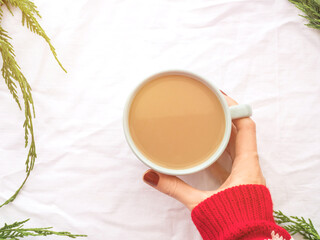 Winter cozy mug of coffee on branches background with hands