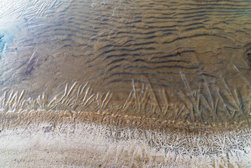 Thin ice on the water of a sand pit with a transparent sandy bottom . Leningrad region, Vsevolozhsk.