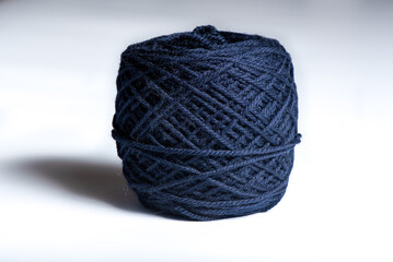 Ball of dark blue yarn on a white background