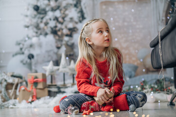 Merry Christmas and Happy Holidays! The morning before Xmas. Portrait of little happy girl wearing Christmas jumper