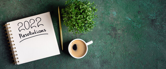 New year resolutions 2022 on desk. 2022 new year resolutions on green background with coffee cup,...