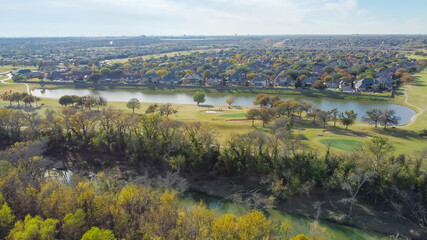 Top view country club golf course and lakeside residential houses near nature park with fall foliage in Carrollton, Texas, USA