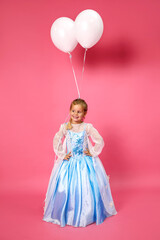 Beautiful happy little girl in a blue dress posing on a pink background with white balloons....