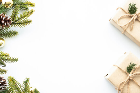 Beautiful Christmas background with two gift boxes, decorate with pine branches and golden balls over white background. Top view with copy space, flay lay.