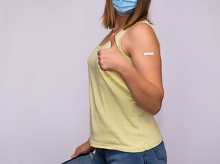 a girl with a patch on her shoulder from vaccination shows a sign of approval. 