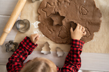 little kid girl in red pajama cooking festive gingerbread in christmas decorated kitchen. christmas cookies