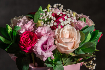 Beautiful bouquet of colorful rose flowers on a black background. Festive flowers concept with copy space. Flowers on a black background. Bouquet of fresh roses, freesias, eustoma and others.