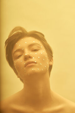 Fashionable teenage girl with rhinestones against yellow background