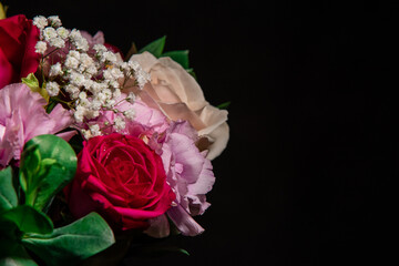 Beautiful bouquet of colorful rose flowers on a black background. Festive flowers concept with copy space. Flowers on a black background. Bouquet of fresh roses, freesias, eustoma and others.