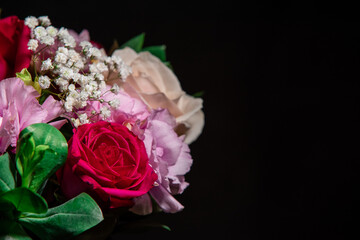 Beautiful bouquet of colorful rose flowers on a black background. Festive flowers concept with copy space. Flowers on a black background. Bouquet of fresh roses, freesias, eustoma and others.