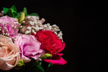 Beautiful bouquet of colorful rose flowers on a black background. Festive flowers concept with copy space. Flowers on a black background. Bouquet of fresh roses, freesias, eustoma and others.