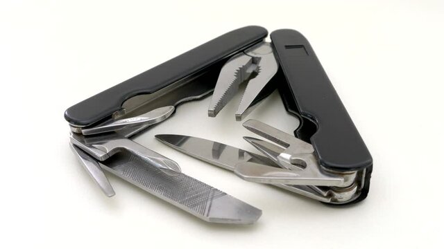 Closeup circular dolly shot of a multi-tool pocket knife &ndash; often used for camping and hiking - opened out and isolated.