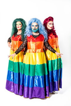 Drag queens with rainbow dresses standing over white background