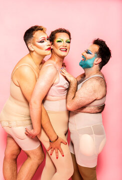 Smiling drag queen and friends by pink background