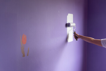 Woman arm painting with roller on tulip stencil wall