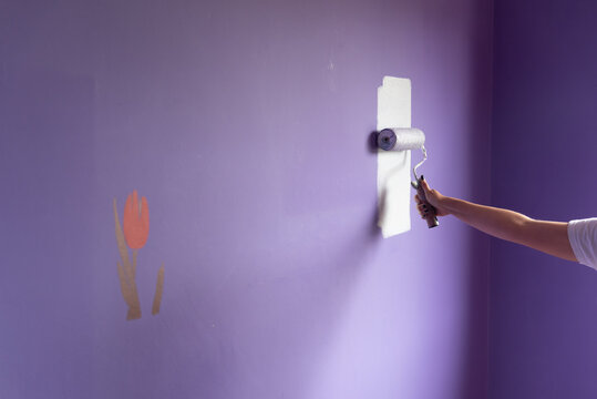 Woman arm painting with roller on tulip stencil wall