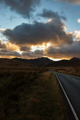A4086 road, at sunset, heading towards the Llanberis Pass with mount Snowdon in the distance. Part of Snowdonia National Park.