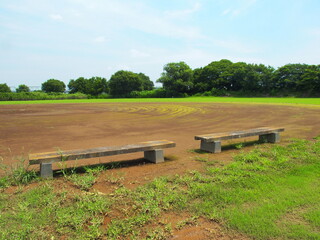 梅雨晴れの平日の河川敷の整地された野球場風景