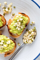 Small toasts with mashed avocado and mung bean sprouts top view