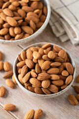 Raw almonds in bowl on wooden table background. Healthy dry nuts