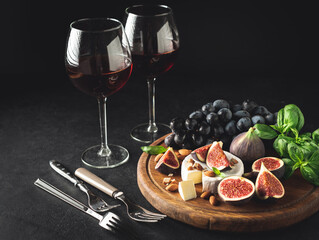 Gourmet wine and cheese appetizer set with camembert and figs. Dark toned image, copy space. Still life